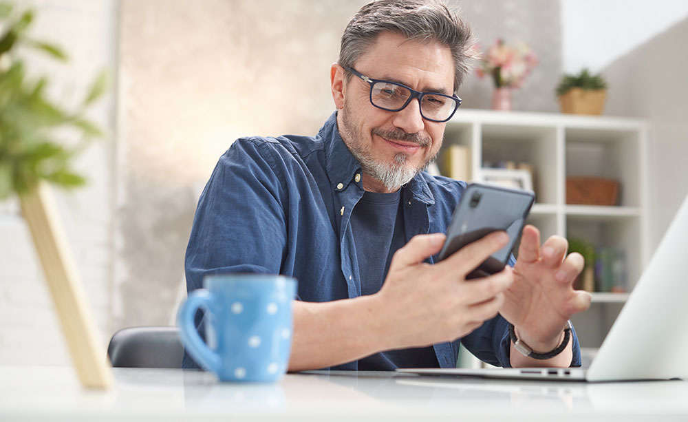 Man smiling at his phone at home