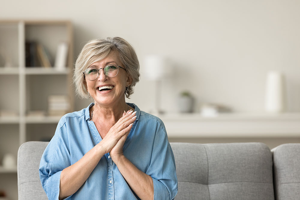 Happy older woman laughing confidently with secure snap-on dentures