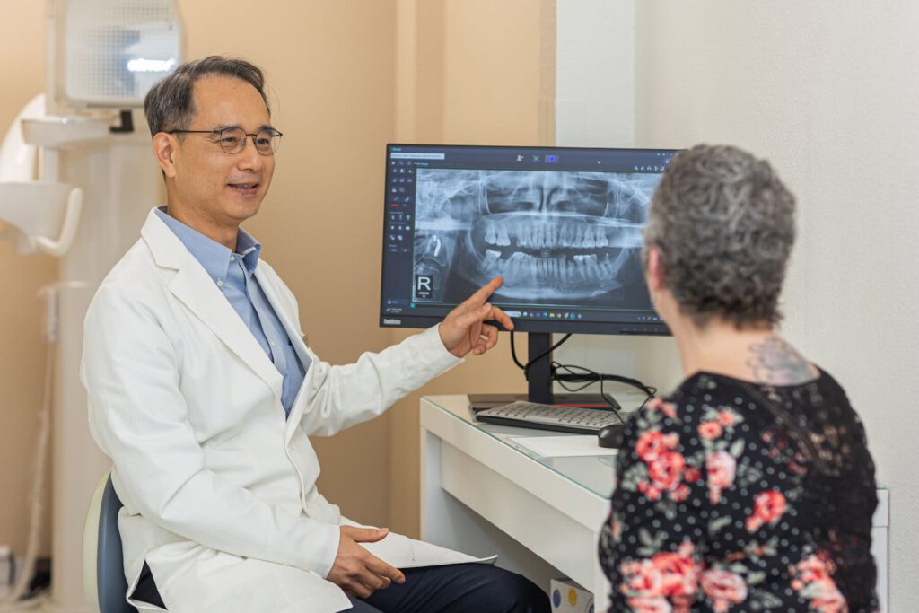 Dr. Sung Wook Yoon reviewing an X-ray with a full-arch dental implant patient at Blooming Dental