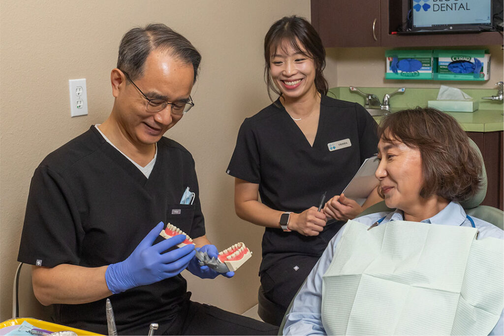 Dr. Sung Wook Yoon showing a dental model to a patient at Blooming Dental