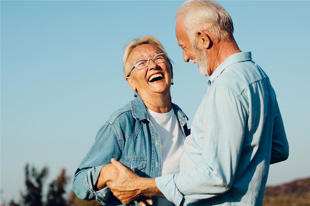 Smiling older couple outdoors enjoying confident smiles